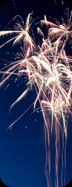celebratory fireworks exploding at late dusk on a deep blue sky